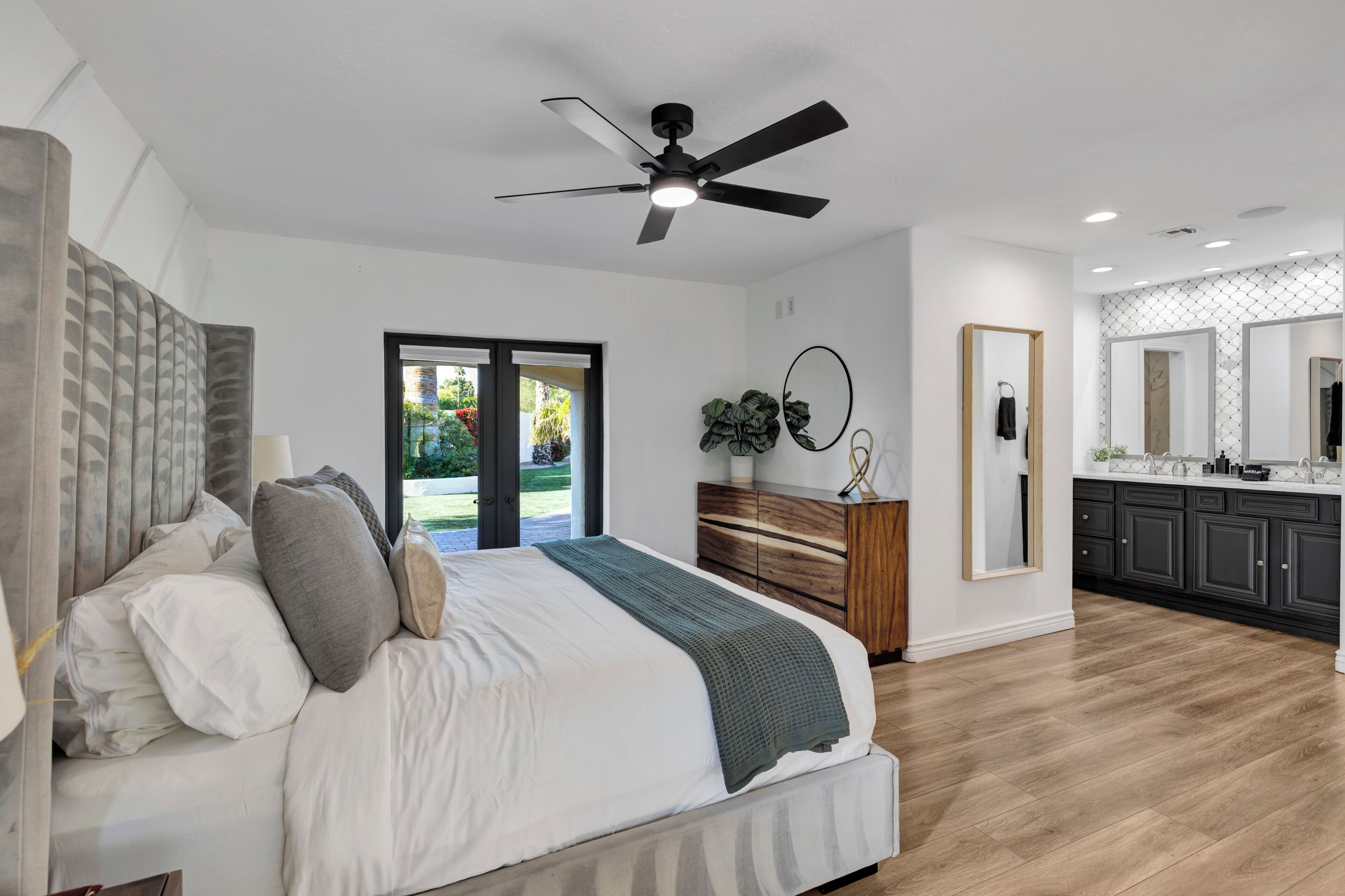 Une chambre moderne avec un grand lit, un ventilateur de plafond et une vue sur l’extérieur.