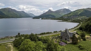 A lake surrounded by mountains, a road, and a church. - Birch Lodge at Aos Sí (Ballachulish)