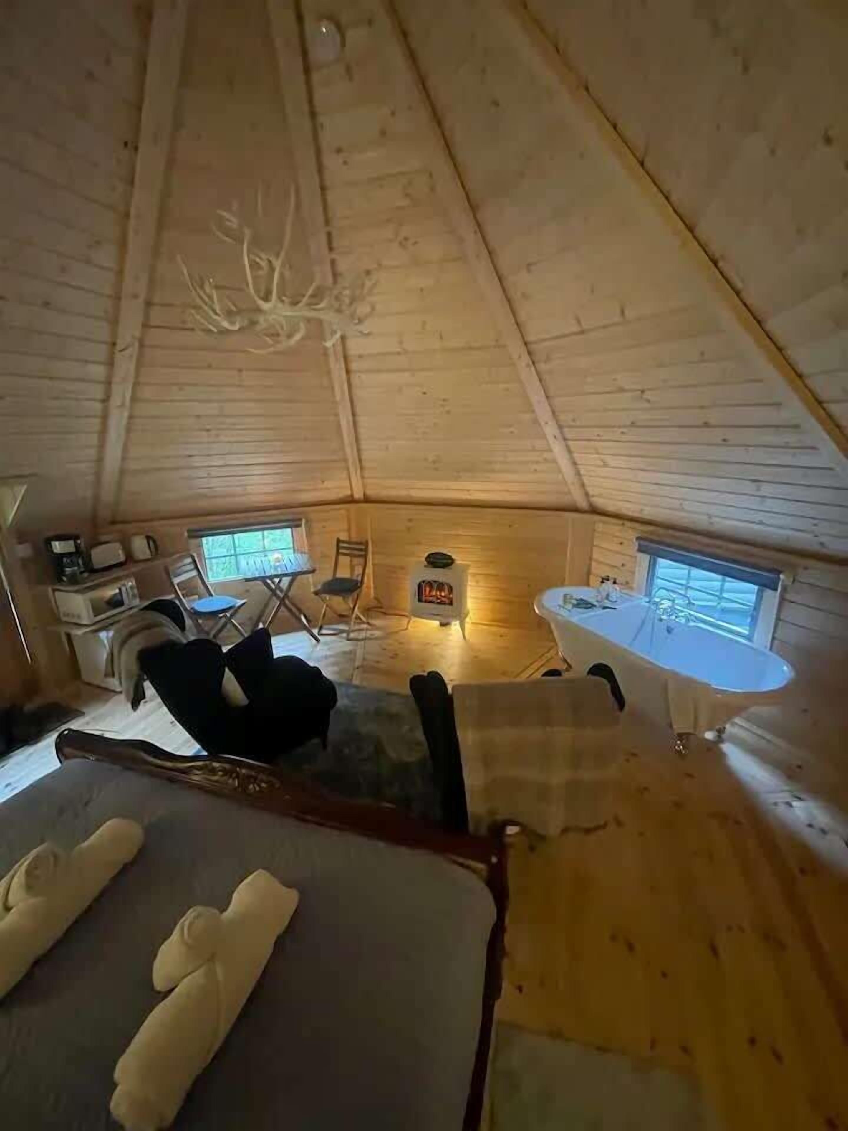 Un acogedor interior de cabaña con una cama, una chimenea, una mesa de comedor y una ventana.