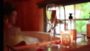A bar area with a glass of champagne, a bottle of perfume, and a bottle of liquor. - Birch Lodge at Aos Sí (Ballachulish)