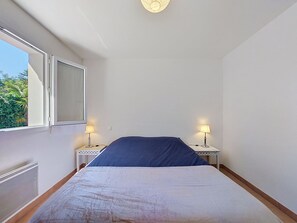 Un dormitorio con una cama, dos mesitas de noche con lámparas, una ventana y una lámpara en el techo.