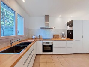 A modern kitchen with a large window, a built-in oven, and a refrigerator. - Les Mouettes by Interhome (Soustons)