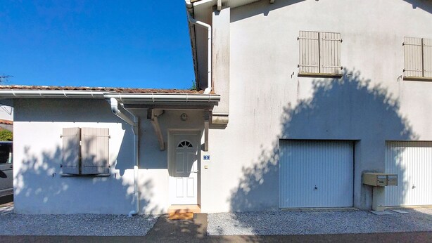 A building with a white facade, a garage door, and a small entrance with a door. - Les Mouettes by Interhome (Soustons)