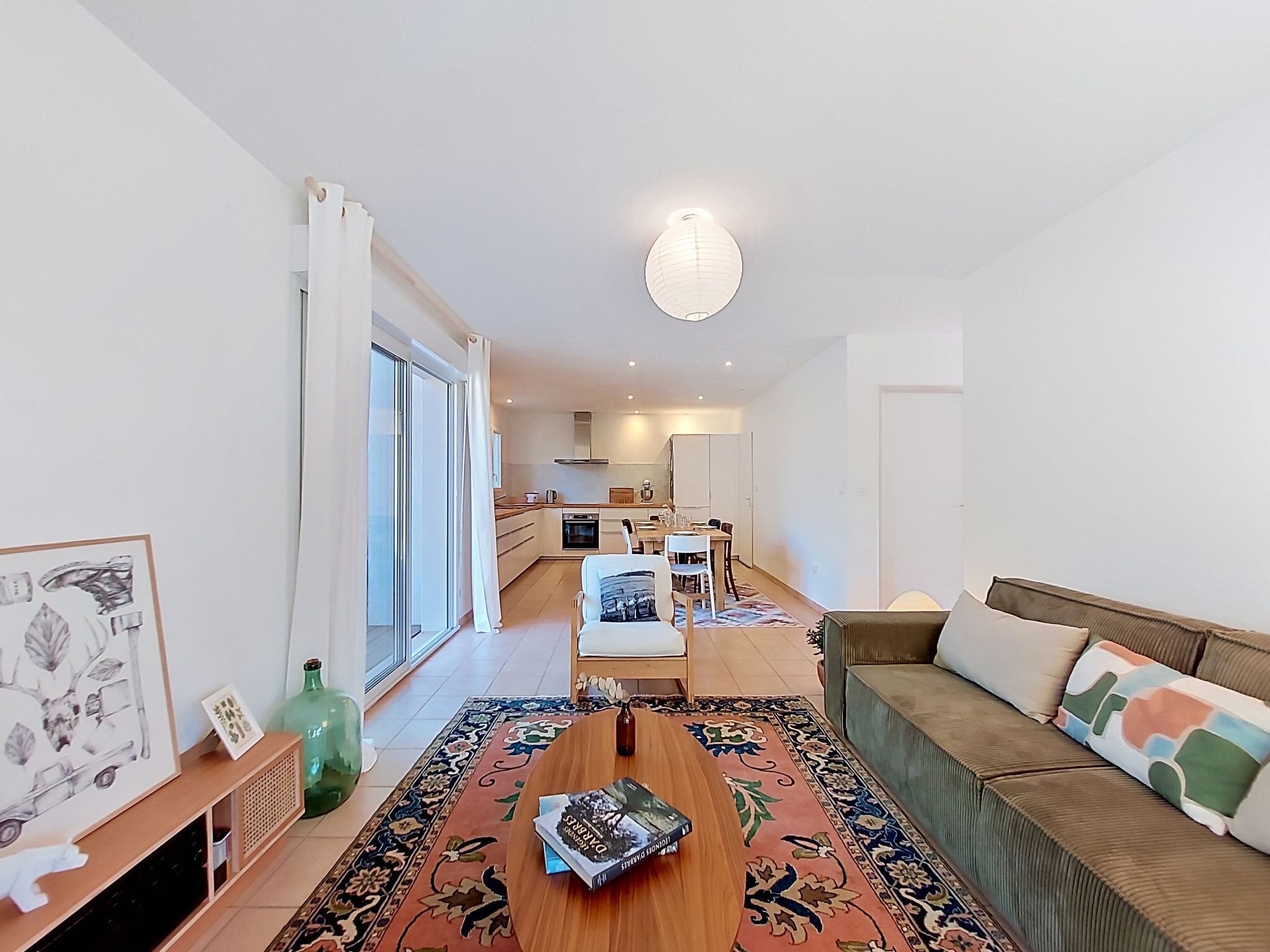 A modern living room with a sofa, a coffee table, and a dining area in the background.