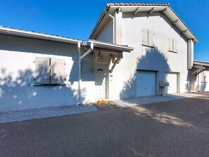 Ein zweistöckiges Gebäude mit Garagenluke, einer kleinen Veranda und einer Tür mit Hausnummer.