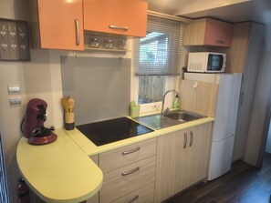 Een kleine keuken met een spoelbak, een magnetron en een fornuis.