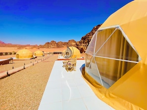 Un resort en el desierto con alojamientos en cúpulas geodésicas, un sendero pavimentado y paisaje árido rocoso.
