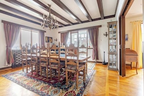 Een eetkamer met een houten tafel, stoelen, een kroonluchter en een piano.