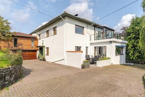 A two-story house with a balcony, a garage, and a paved driveway. - 6-bedroom luxurious house in Vestland for your getaway to the fjords of Norway (Vestland)