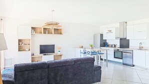 Ein modernes Wohnzimmer mit einer Couch, einem Fernseher und einem Essbereich mit Stühlen und einem Tisch.