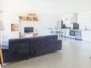 Ein modernes Wohnzimmer mit einer Couch, einem Fernseher und einem Essbereich mit Stühlen und einem Tisch.