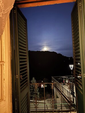 Un balcone aperto con vista su una collina e un lampione.
