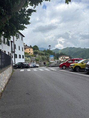 Una strada con auto parcheggiate, un attraversamento pedonale e edifici con insegne.