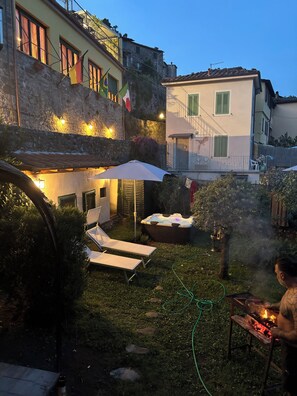 Un cortile con poltrone, una vasca idromassaggio e un angolo barbecue.