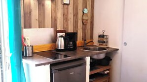 Una cucina compatta con rivestimenti in legno, lavastoviglie, macchina del caffè e un piccolo lavello.