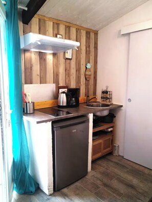 A compact kitchen with wooden paneling, a dishwasher, a coffee maker, and a small sink. - Studio with terrace Port de St Goustan (Auray)