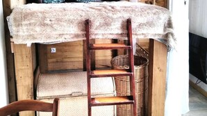 Una camera accogliente in stile baita, con un letto a castello, pareti in legno, una scala e un cesto di vimini.