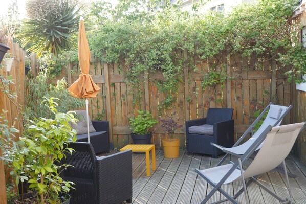 Una terraza de madera con mobiliario exterior, incluyendo dos sillas y una mesita.