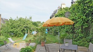 Une terrasse en bois avec des meubles d’extérieur, une table et un parasol jaune.