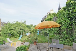 Eine Holzterrasse mit Gartenmöbeln, einem Tisch und einem gelben Sonnenschirm.