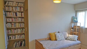 Une chambre à coucher avec un lit en bois, une bibliothèque et une fenêtre avec des rideaux.