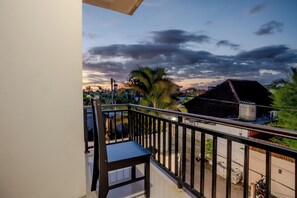 A balcony with a metal railing, a chair, and a view of a residential area with houses and a palm tree. - Cedil Private 3BR Pool Villa Seminyak (Kabupaten Badung)