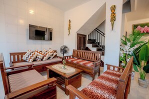 A living room with a sofa, a coffee table, a TV, and a staircase. - Cedil Private 3BR Pool Villa Seminyak (Kabupaten Badung)