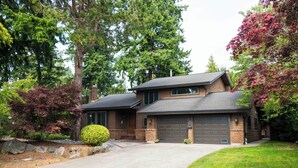 A two-story house with a garage, surrounded by trees and a well-maintained lawn.