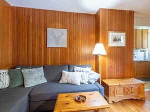 Ein Wohnzimmer mit einer Couch, einem Couchtisch, einer Lampe und Holzvertäfelung an den Wänden.