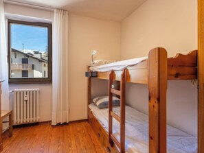 Ein Schlafraum mit Etagenbett, Fenster, Heizkörper und Holzboden.