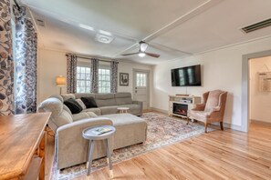 A living room with a sofa, ottoman, and a TV.