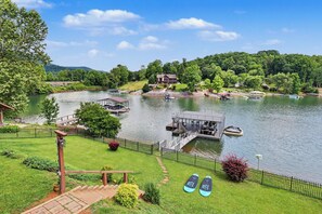 Una proprietà sul lago con un pontile, barche e una casa.