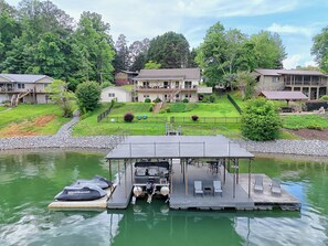 Une jetée dotée d’un espace de repos abrité, un bateau et une maison avec une grande terrasse et plusieurs niveaux.