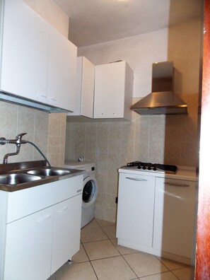 A compact kitchen with a washing machine, a stove, and a sink. - Spacious apartment with side sea view (Bibione)