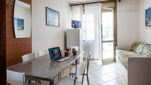 Una habitación con una mesa de comedor, sillas, una computadora portátil, una cama y un televisor.