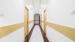 Un pasillo largo y estrecho con paredes blancas y puertas de madera a ambos lados.