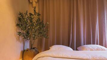 A hotel room with a bed, a potted plant, and a curtain.