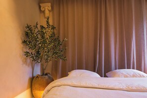 Ein Schlafzimmer mit einem Bett, einer Topfpflanze und einem Vorhang.