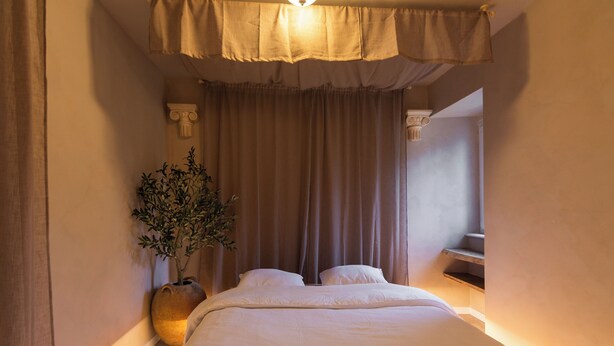 Een slaapkamer met een bed, gordijnen, een plant en een trap.