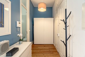 Ein schmaler Flur mit einem weißen Kleiderschrank, einer Deckenleuchte, einem Wandheizkörper und einer Pflanze.