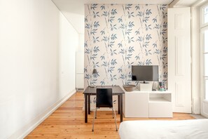 Une chambre moderne avec un plancher en bois, un bureau avec une chaise, une télévision et un lit.