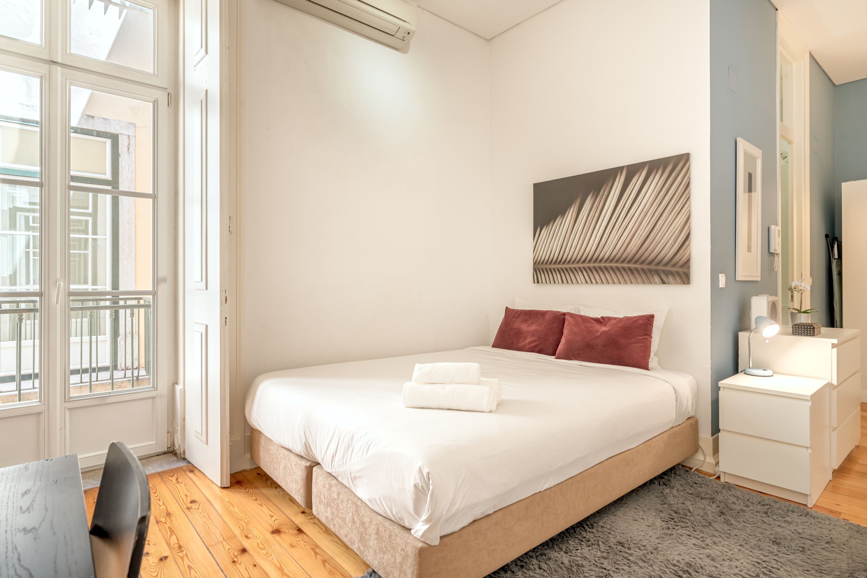 Una camera da letto con un letto grande, un comodino con una lampada, un quadro appeso al muro e una finestra con vista sull'esterno.