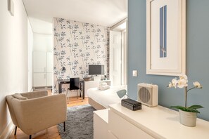 Une chambre d’hôtel moderne équipée d’un lit, d’un bureau, d’une chaise, d’une orchidée en pot et d’un radiateur.