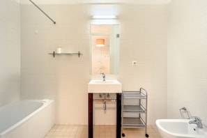 Ein Badezimmer mit Badewanne, Waschbecken, Spiegel und Dusche.
