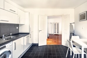 Eine moderne Küche mit Waschmaschine, Spüle und Essbereich mit Stühlen.
