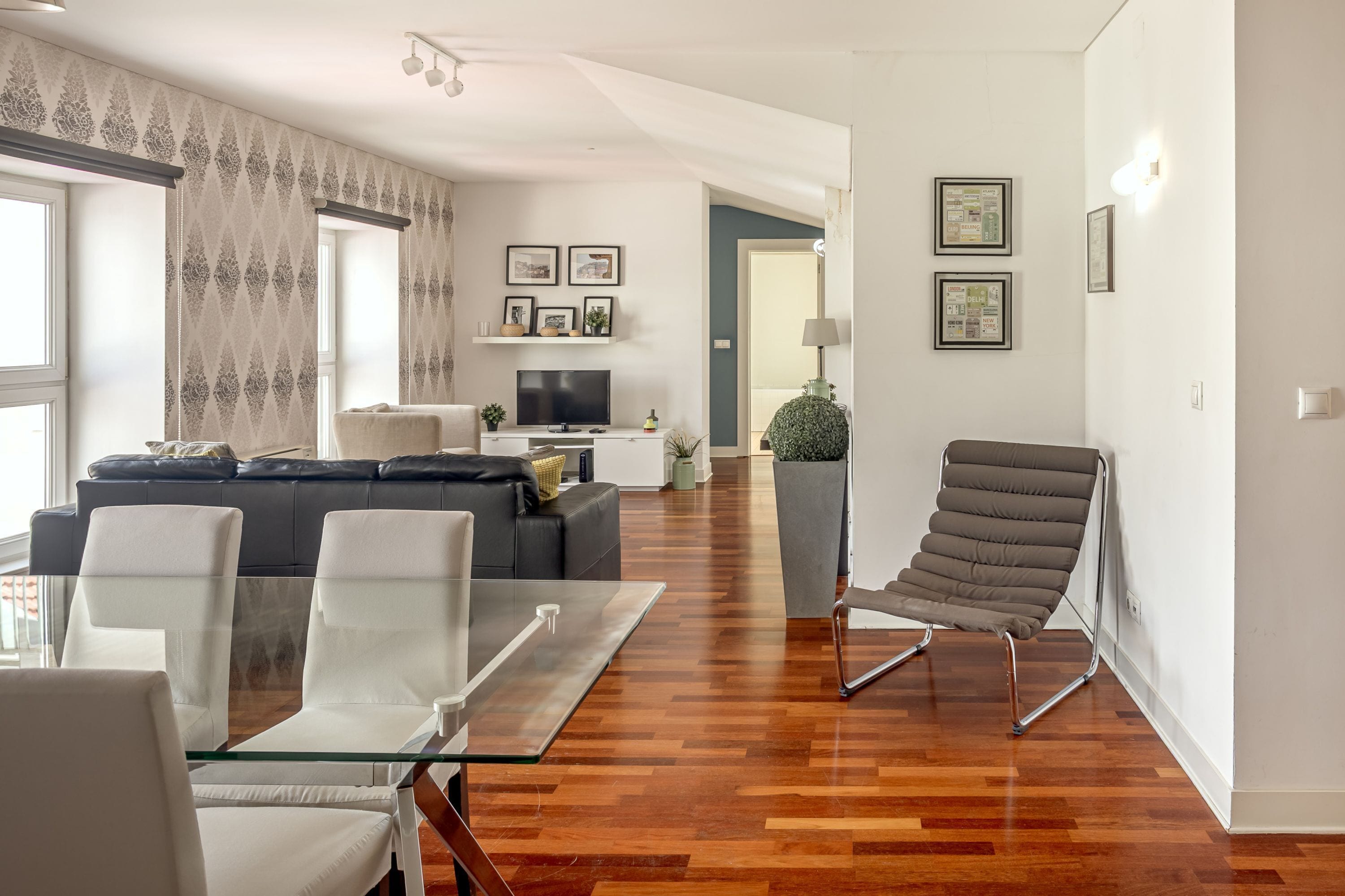 Un salon moderne comprenant un canapé, des fauteuils, un téléviseur et un coin repas.