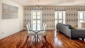 Un'ampia zona giorno con un tavolo da pranzo in vetro, un divano grigio e carta da parati decorata.