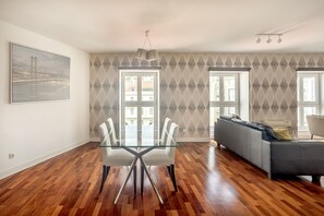 A spacious living area with a glass dining table, a gray sofa, and patterned wallpaper. - Downtown Riverside V by Homing (Lisbon)