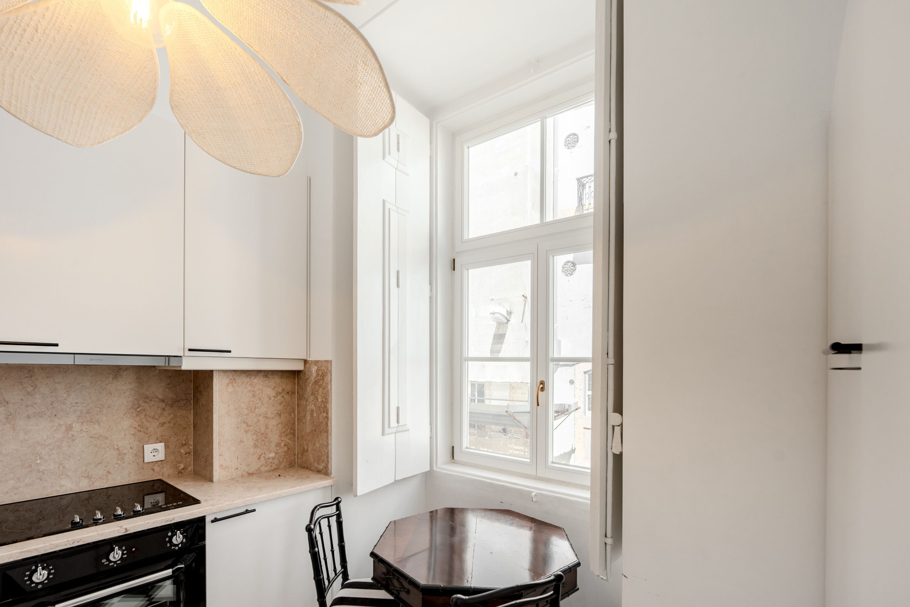 A kitchen with white cabinets, a black stove, and a dining table with chairs.
