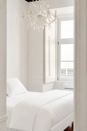 Ein Schlafzimmer mit zwei Betten, einer Pendelleuchte und einem Fenster.